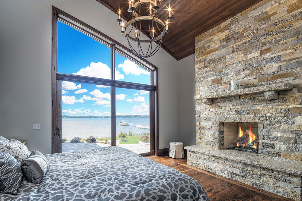 Lake view bedroom with stone fireplace
